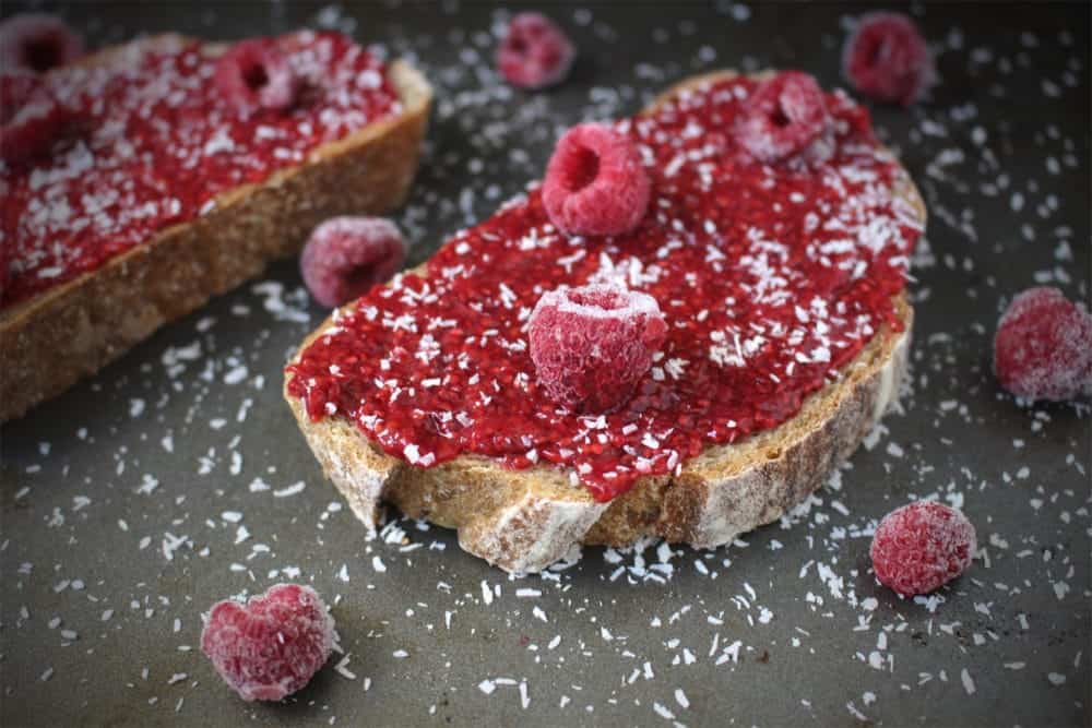 Jam on toast sprinkled with coconut and fresh raspberries.