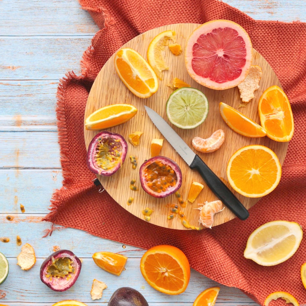 Fresh sliced Citrus Fruits and Passon Fruit on a round cutting board over an orange napkin