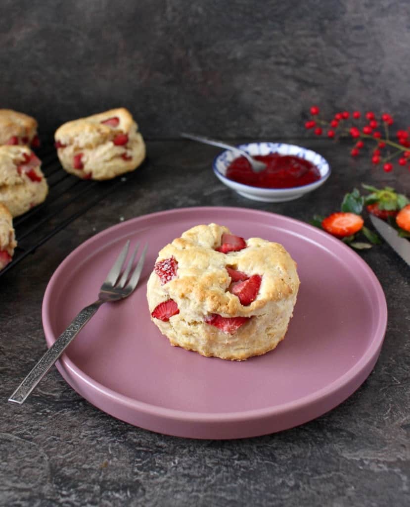 One scone on a pink plate with a fork