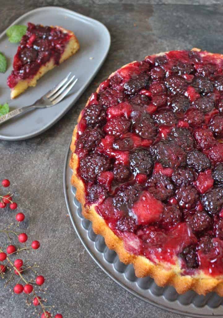 Half of the cake on the baking pan with a slice on a grey plate