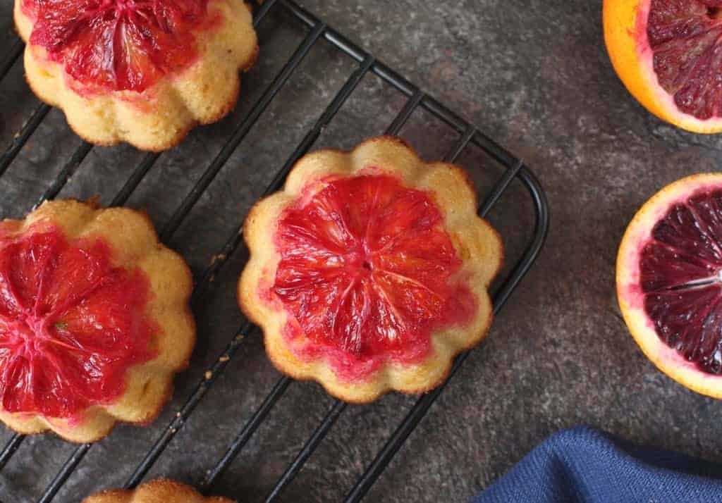 Small cakes on a black cooling rack from above on a dark grey surface.