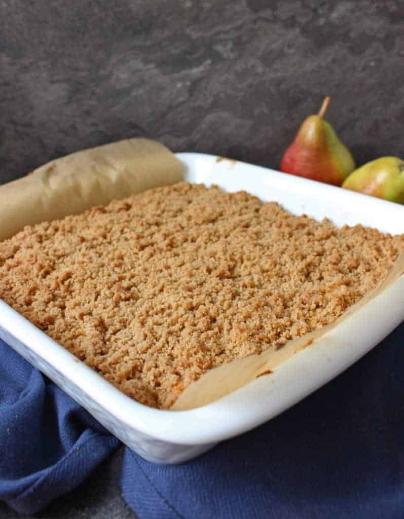 Pear Crumble Cake in a white ceramic dish over a navy napkin.