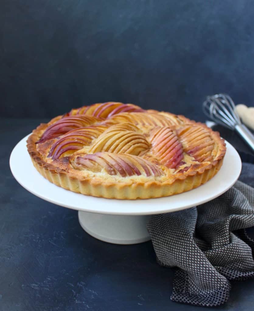 Peach Tart on a white cake stand with a grey napkin below.