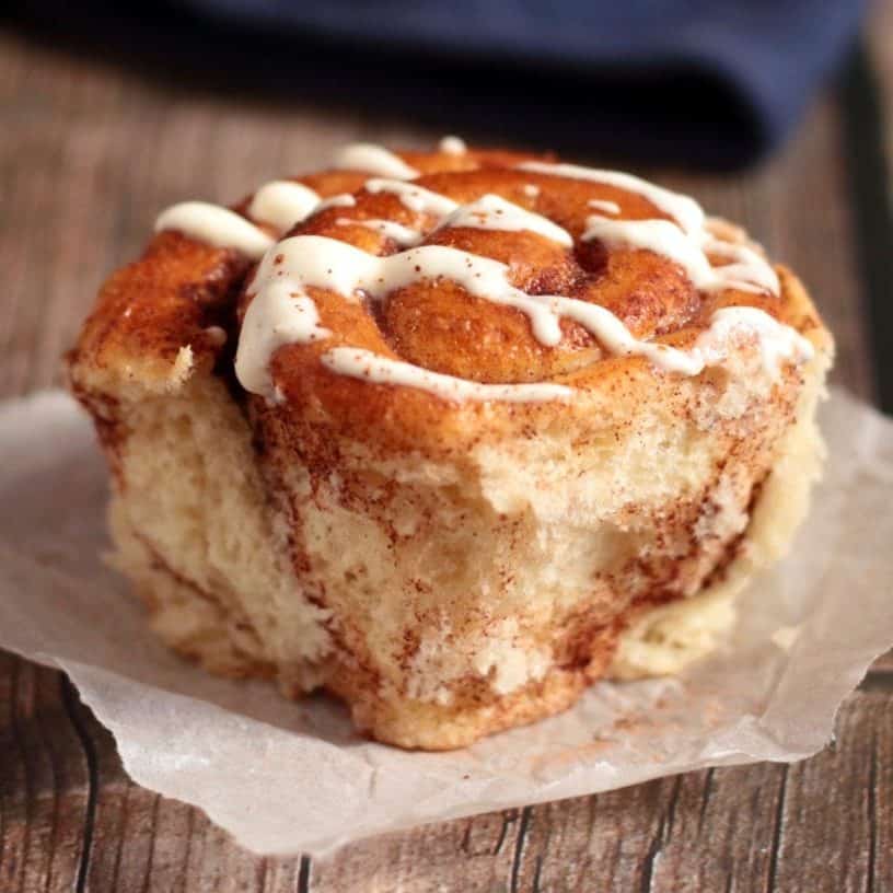 One cinnamon roll on a piece of baking paper