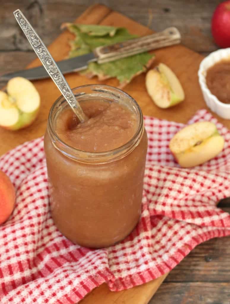Applesauce in a glass jar with a spoon in it.