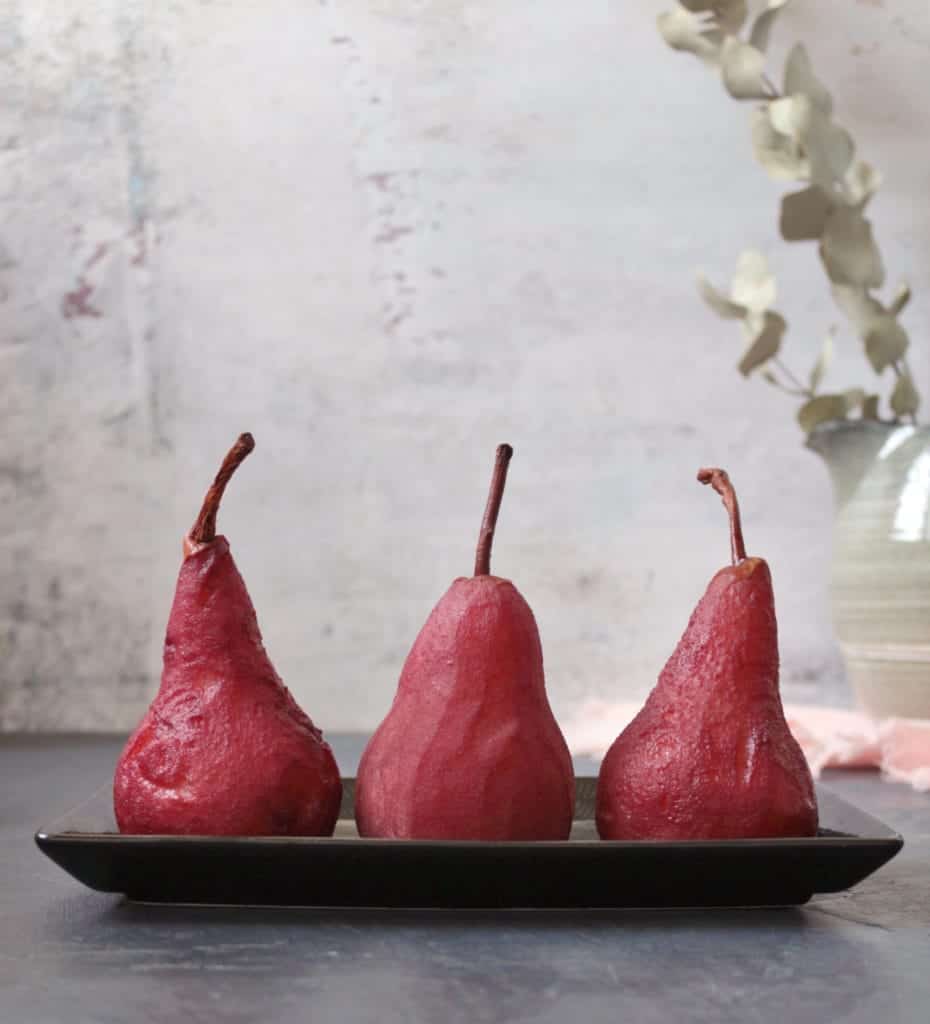 3 Pears standing on a black plate