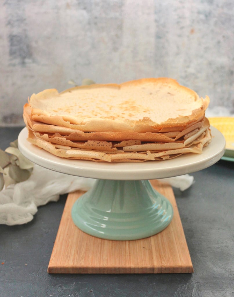 Stack of crepes on a beige and green cake stand.