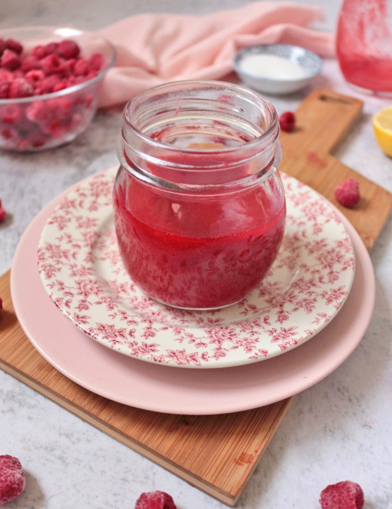 Coulis in a clear jar over two pink plates.