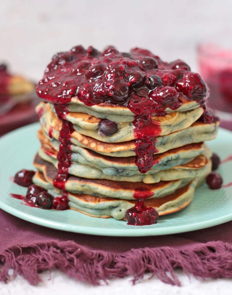 Close up on Pancakes with Blueberry Sauce dripping along the side of the stack.