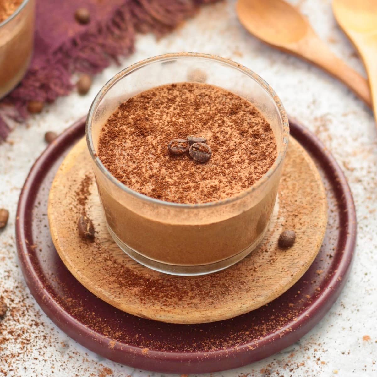 One mousse cup over a wooden plate and a purple plate