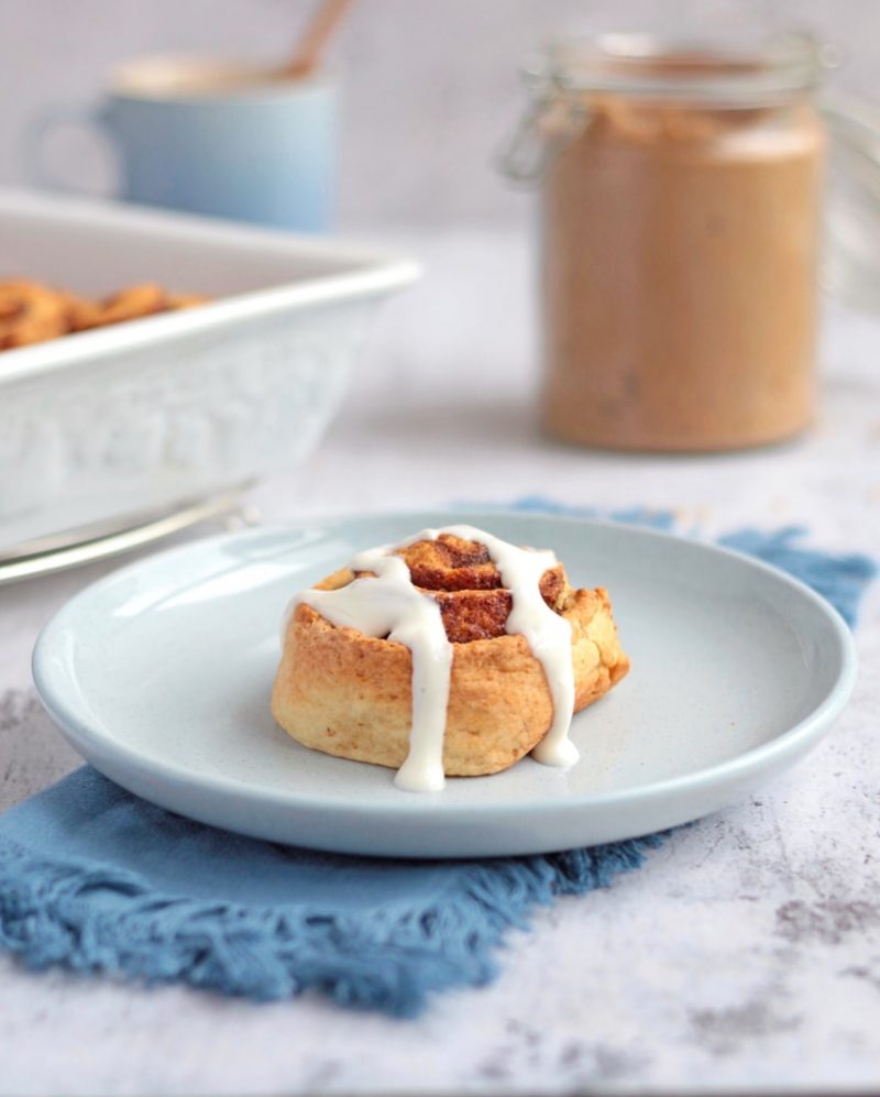 One Roll on a blue plate with Greek Yogurt Icing drizzled over