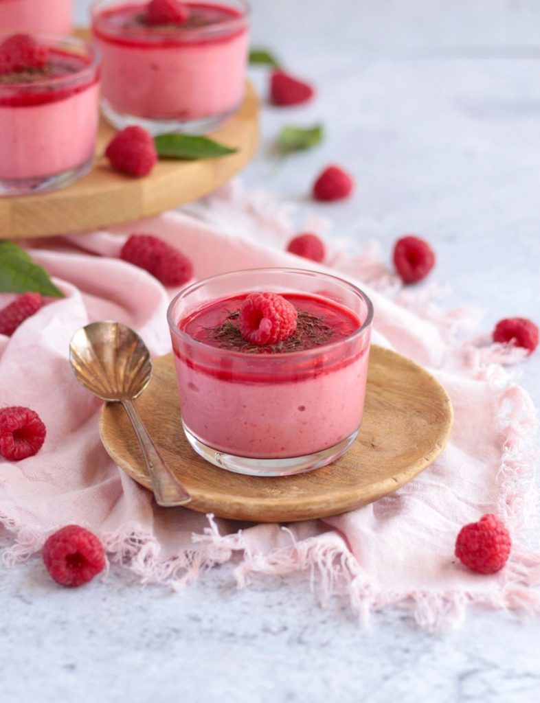 One mousse placed over a small wooden plate with a spoon.