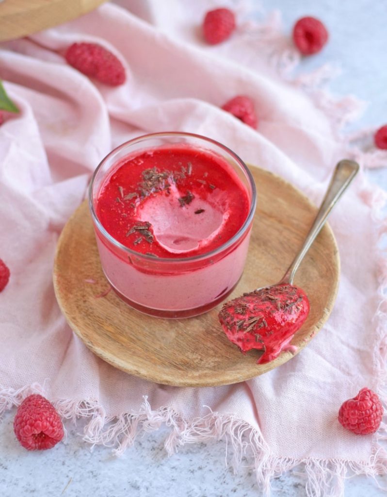 A spoon of mousse taken off the cup and dripping over the plate.