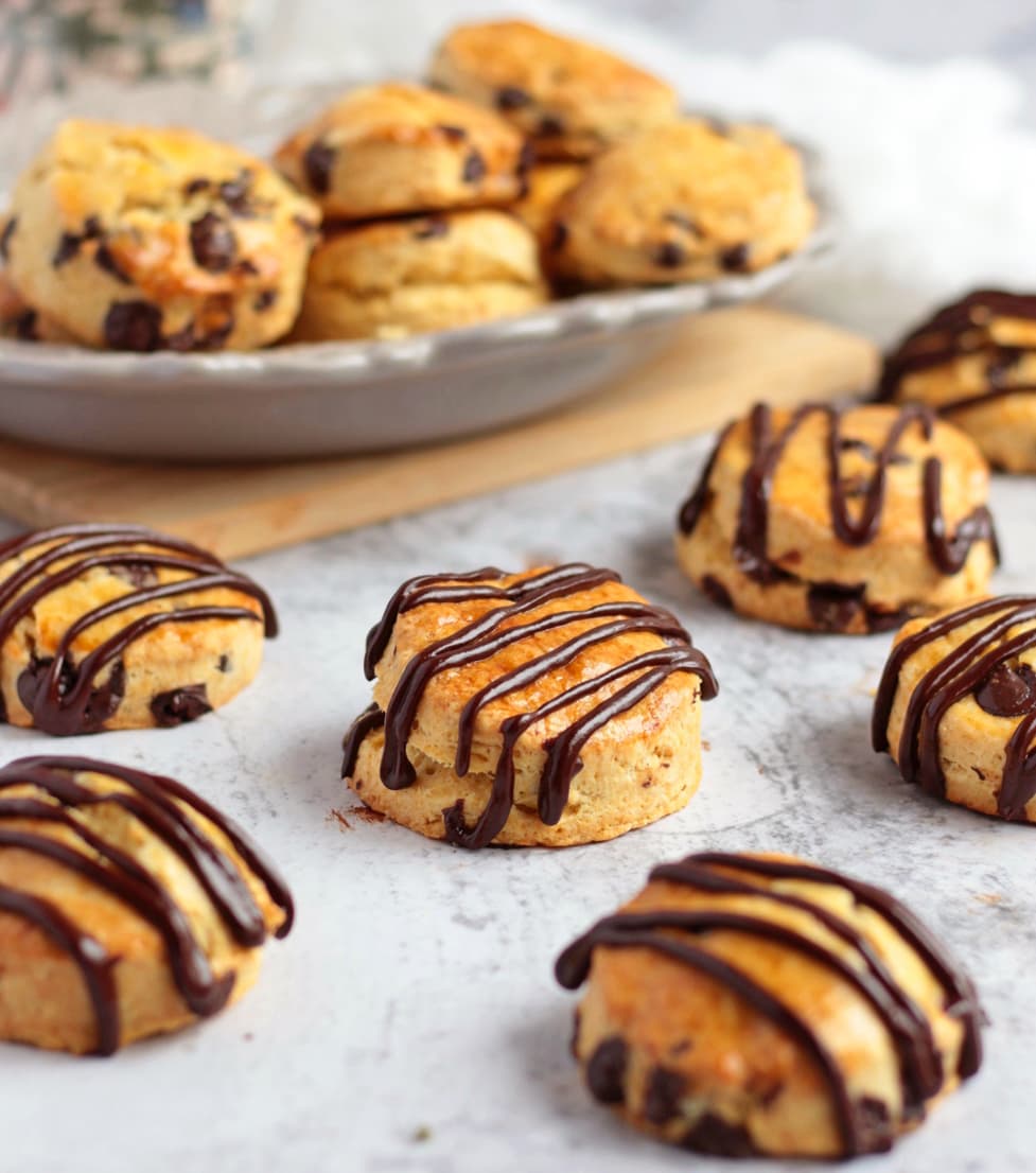 Chocolate Chip Scones topped with a chocolate ganache drizzle on a grey surface