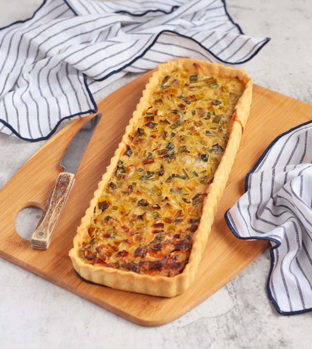 Finished savoury tart on a board with a knife