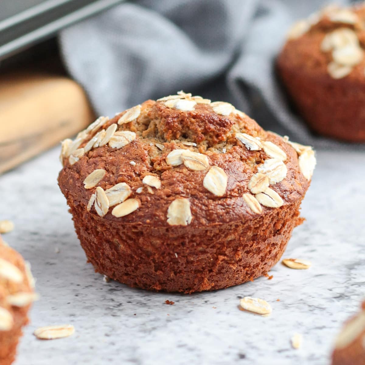 One oatmeal banana muffin next to the muffin pan.