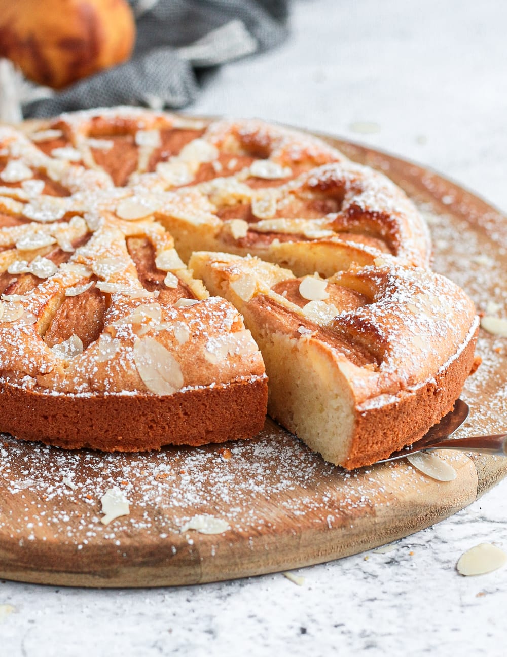 A slice of the pear cake cut off on a wooden board.