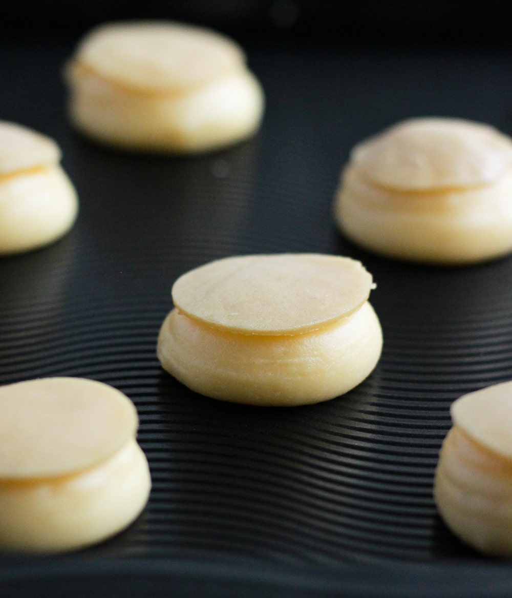 Unbaked choux topped with raw craquelin on a baking tray