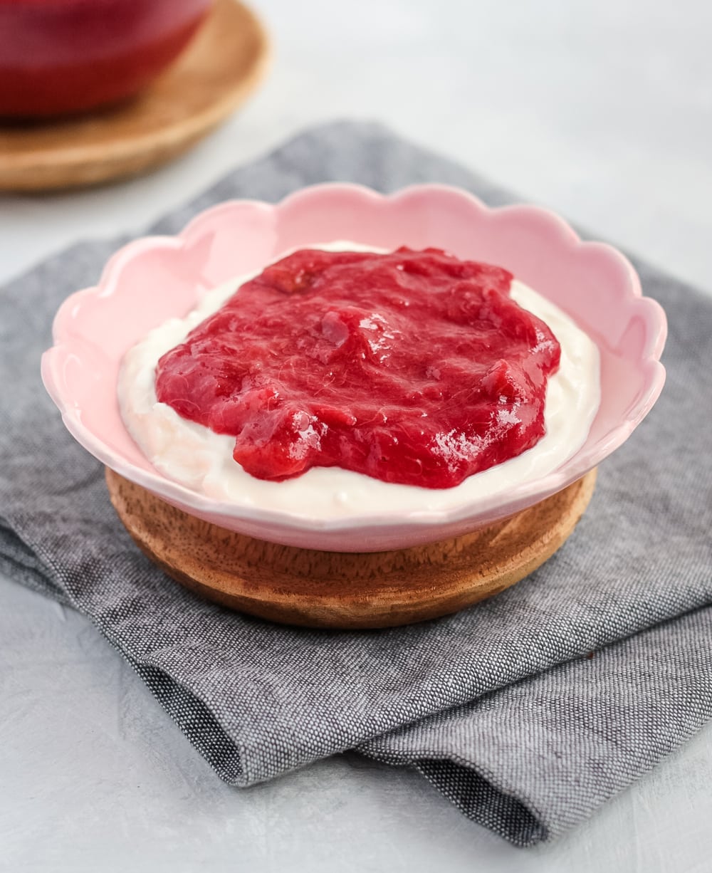 Rhubarb compote on top of greek yogurt in a pink bowl