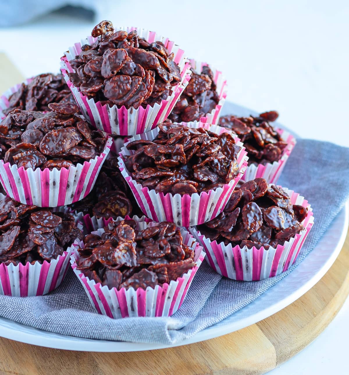 Stack of cornflakes cakes over a grey napkin and wooden board.