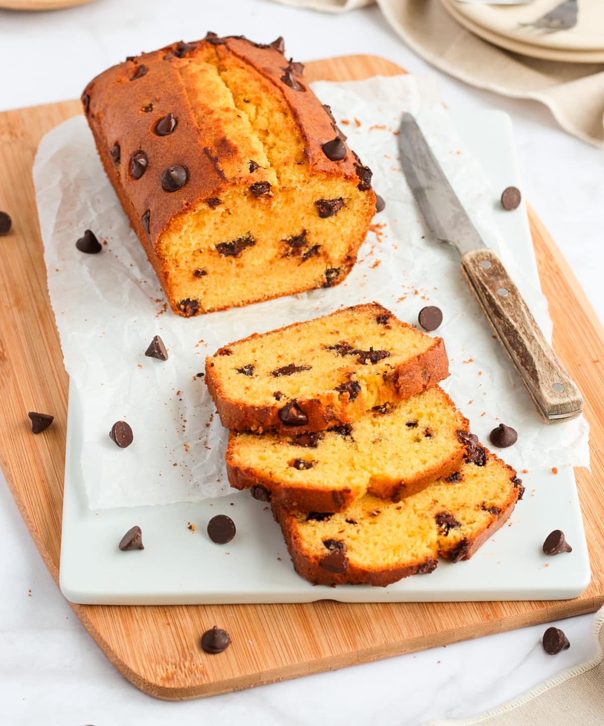 3 slices of cake laying next to the loaf on a white and wooden board