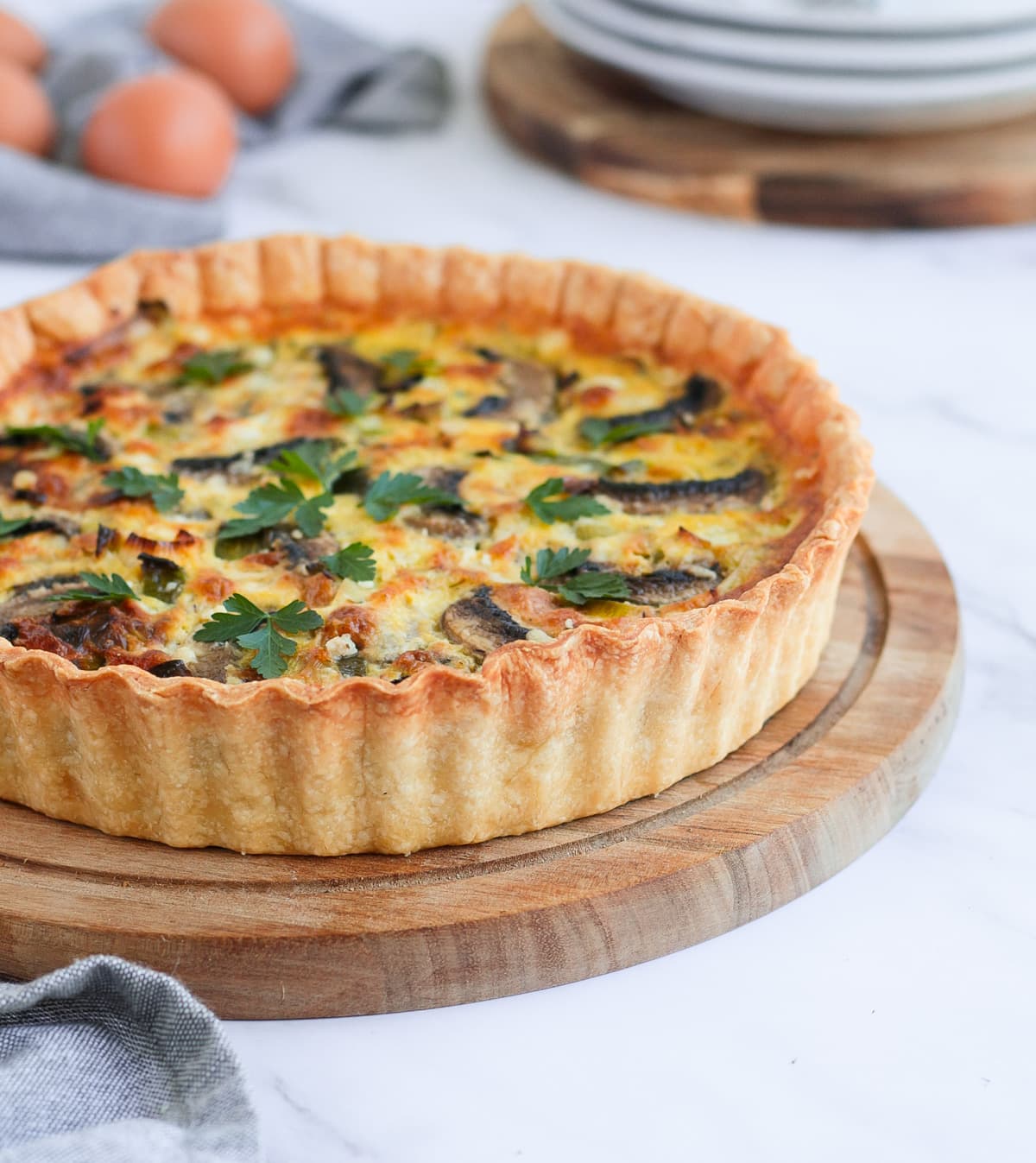 Side view on the quiche over a wooden round board