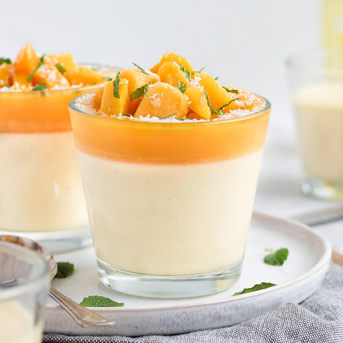 Close up on a panna cotta in a small glass cup placed over a white plate