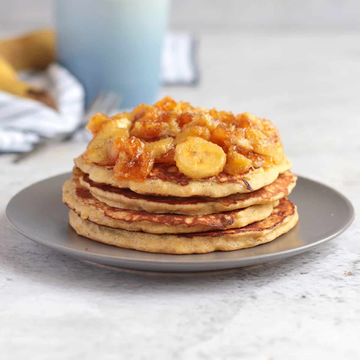 Banana Pancakes stacked on a grey plate and topped with honey caramelised bananas.