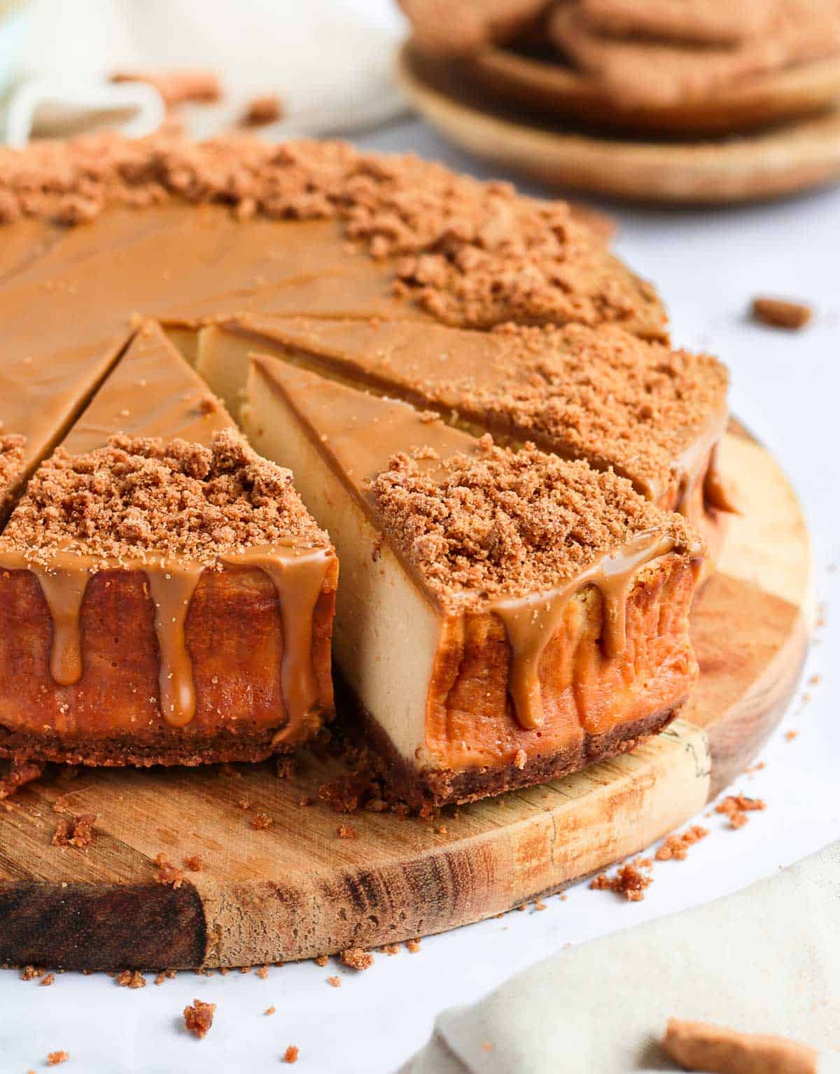 Side view of the cheesecake on a wooden board with 3 pieces sliced off.