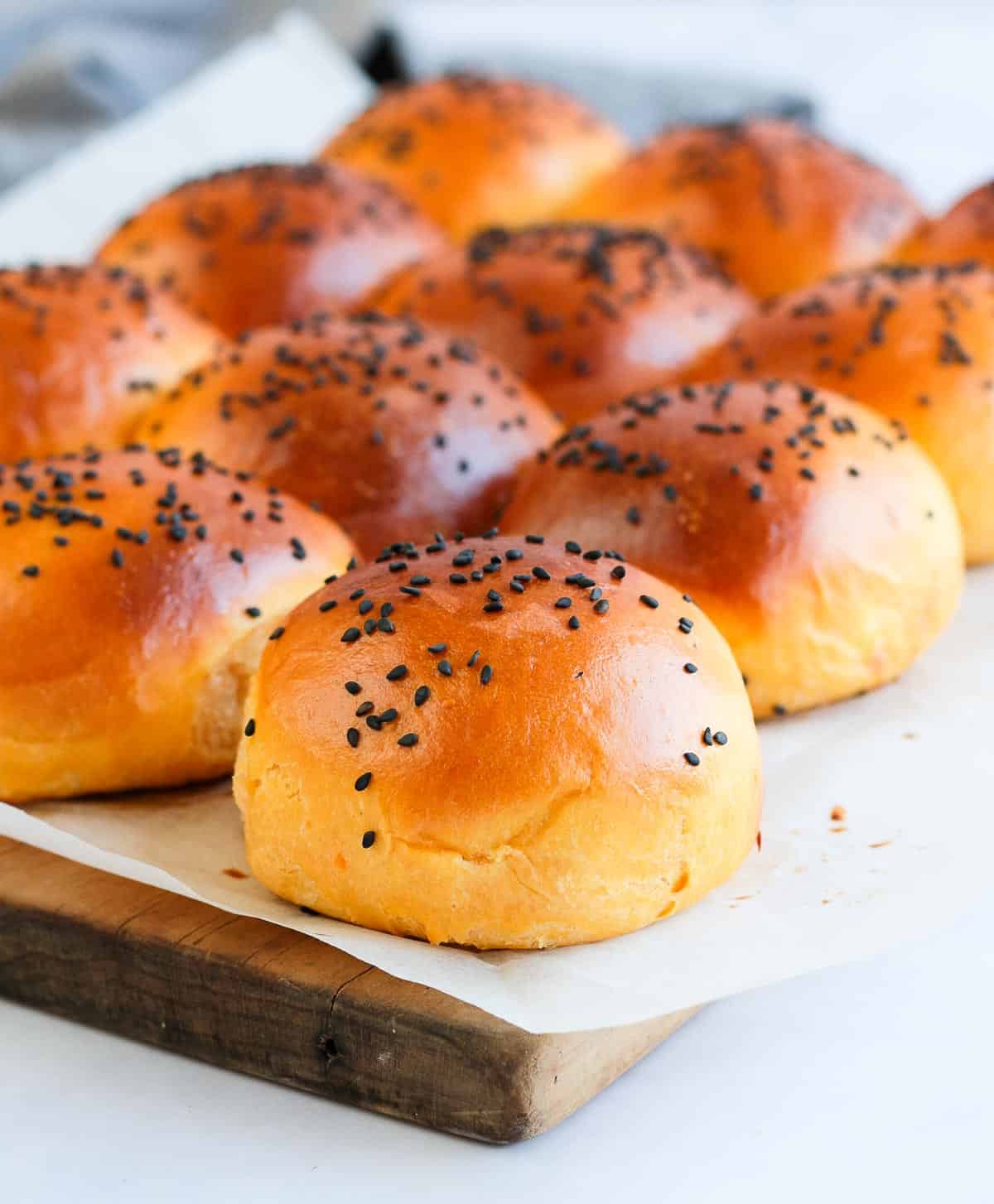 Close up on one bun over baking paper and a wooden board.