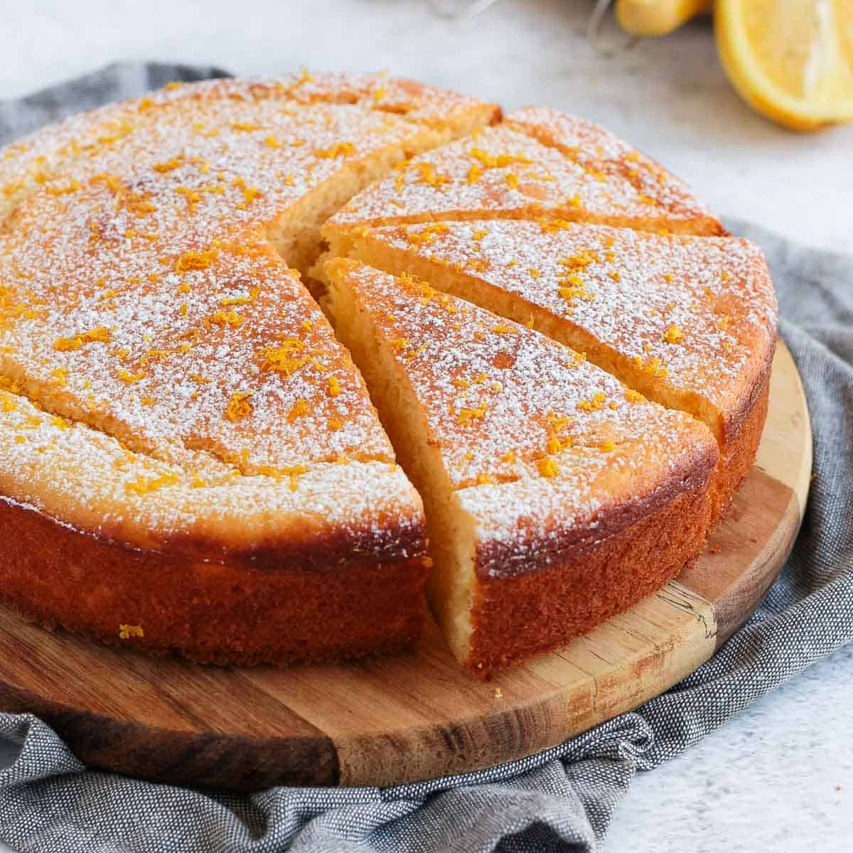 Ricotta cake with 3 slices cut out on a wooden board over a grey napkin.