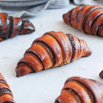 Close up on one chocolate rugelach on a grey surface.
