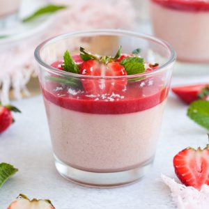 Close up on the dessert in a glass, topped with fresh strawberries and mint.