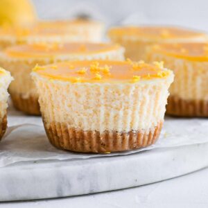 Close up on one mini lemon cheesecake over a marble board.