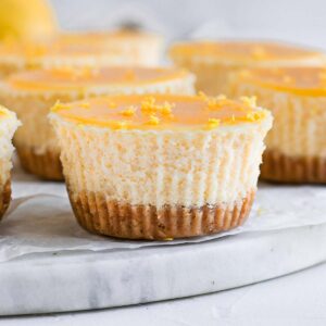 Close up on one mini lemon cheesecake over a marble board.