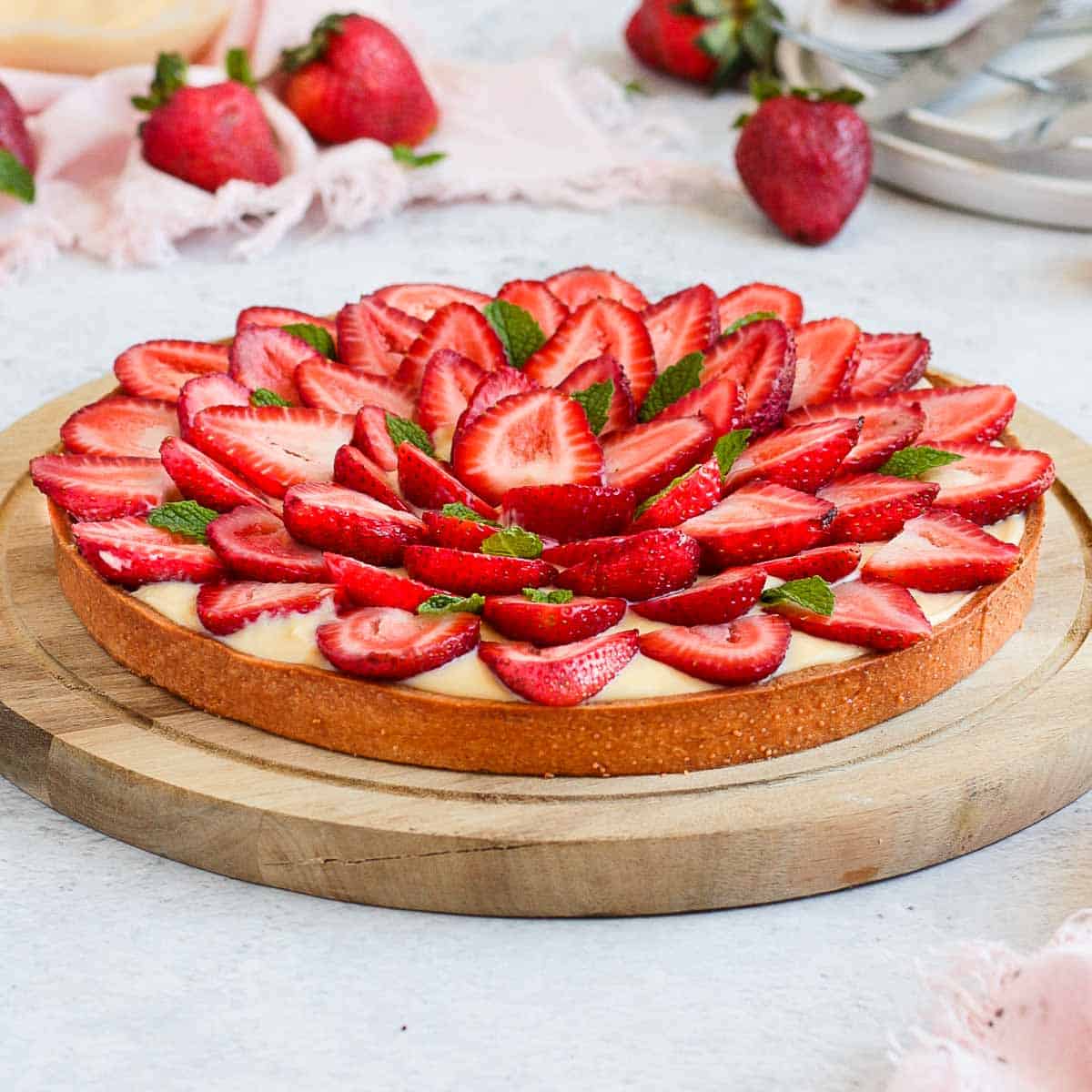Close up on the strawberry tart placed over a wooden round board.