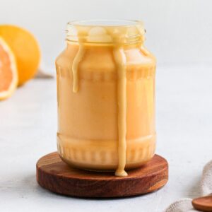 Orange Curd in a glass jar with drips.