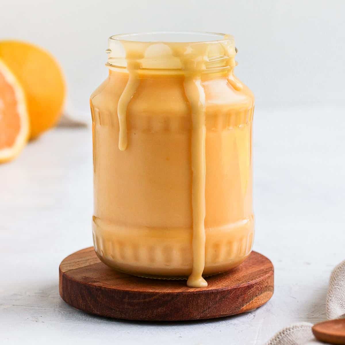 Orange Curd in a glass jar with drips.