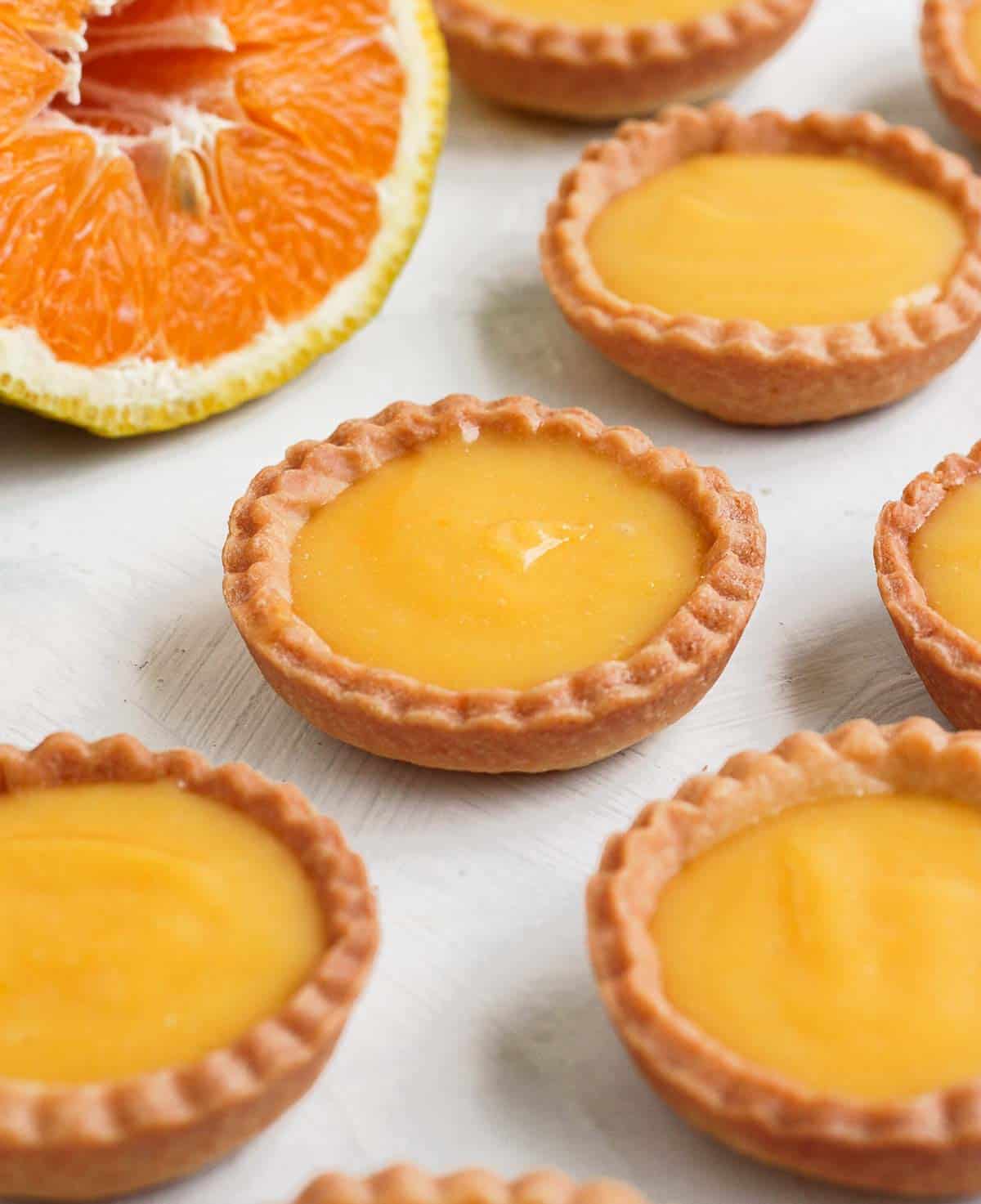 Orange Tarts on a white surface with an orange sliced in half.