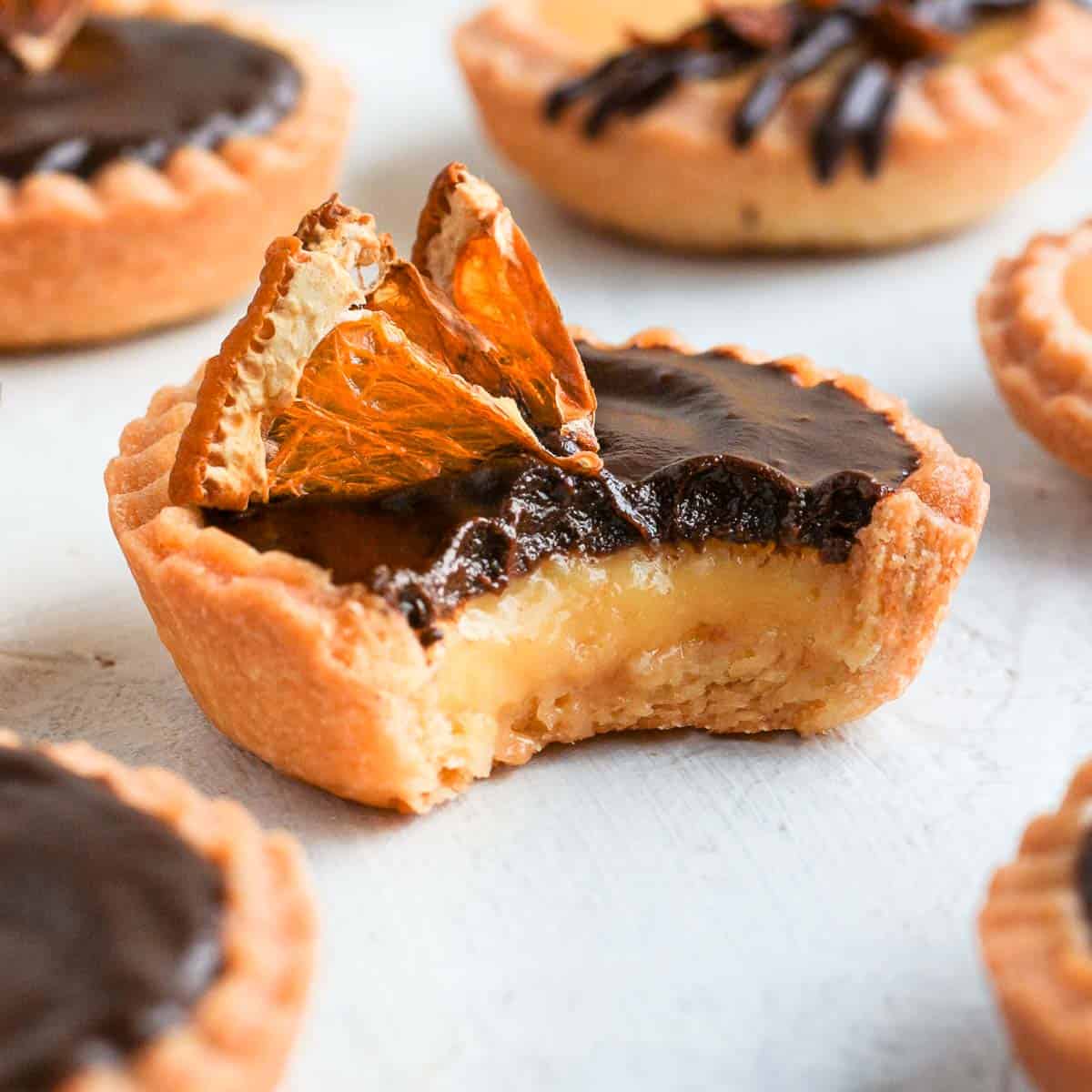 One chocolate orange tartlet with a bite taken off.