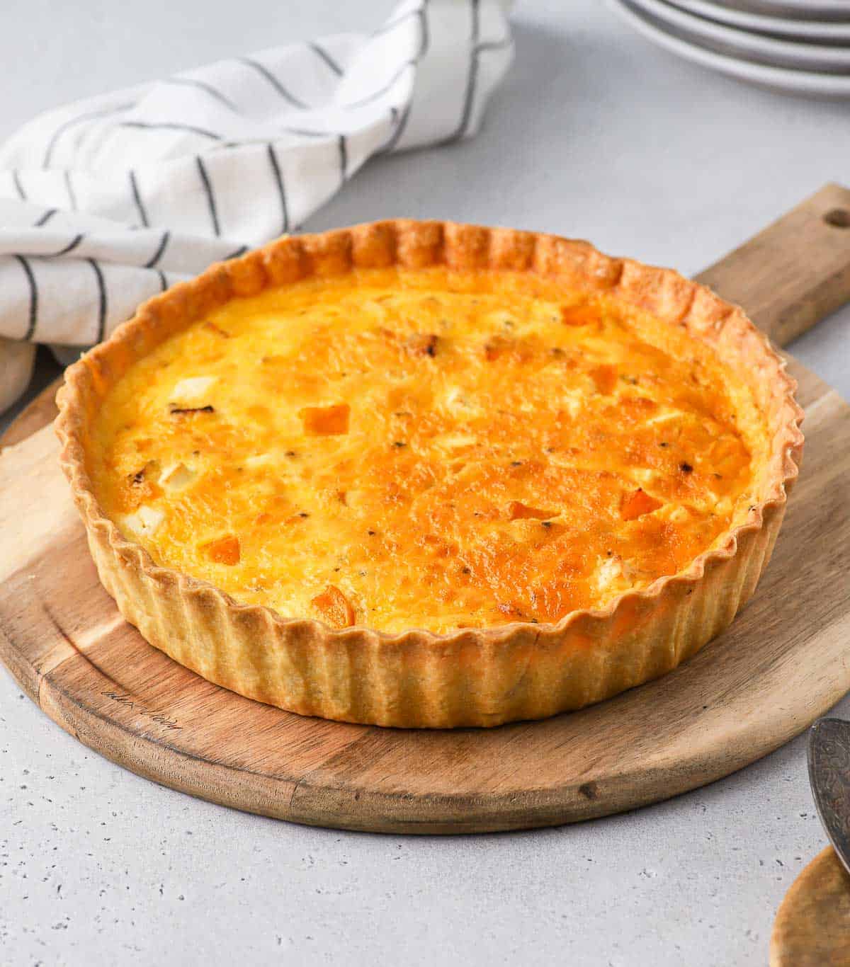 Quiche on a wooden round board.