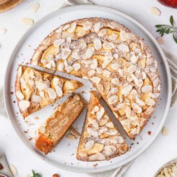 Apple and Almond Cake on a white plate seen from above with 3 slices cut off.