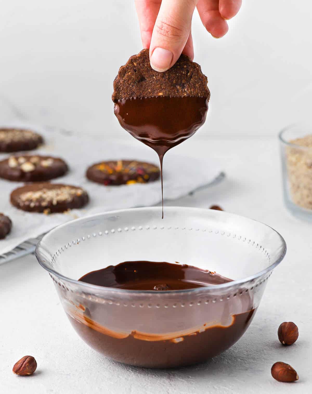 Dipping one cookie in melted chocolate.