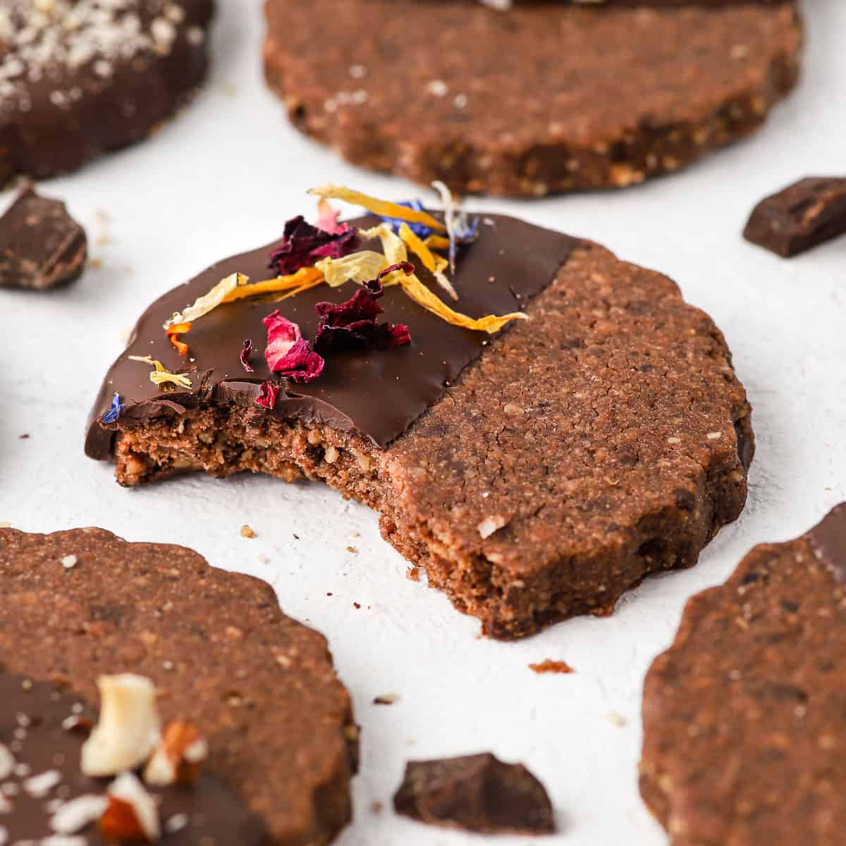 Close up on a chocolate hazelnut shortbread cookie with a bite taken off.