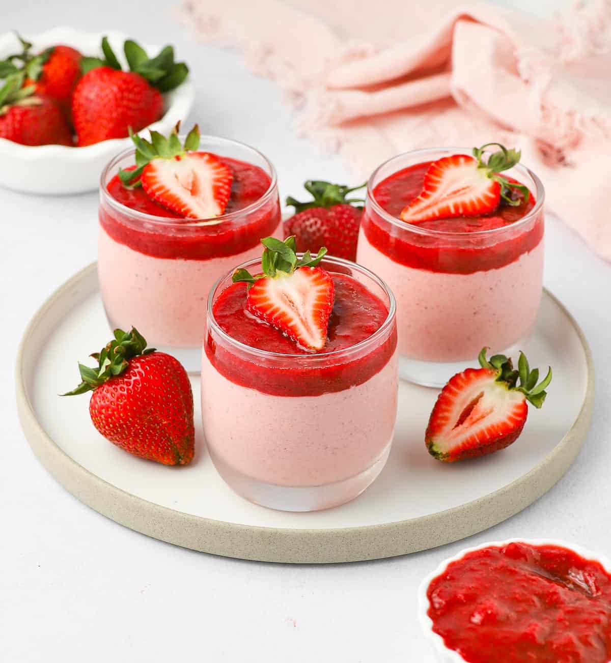 3 filled cups on a white plate with fresh strawberries.
