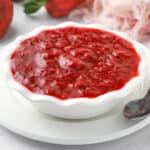 Strawberry compote in a small white bowl over a white plate.
