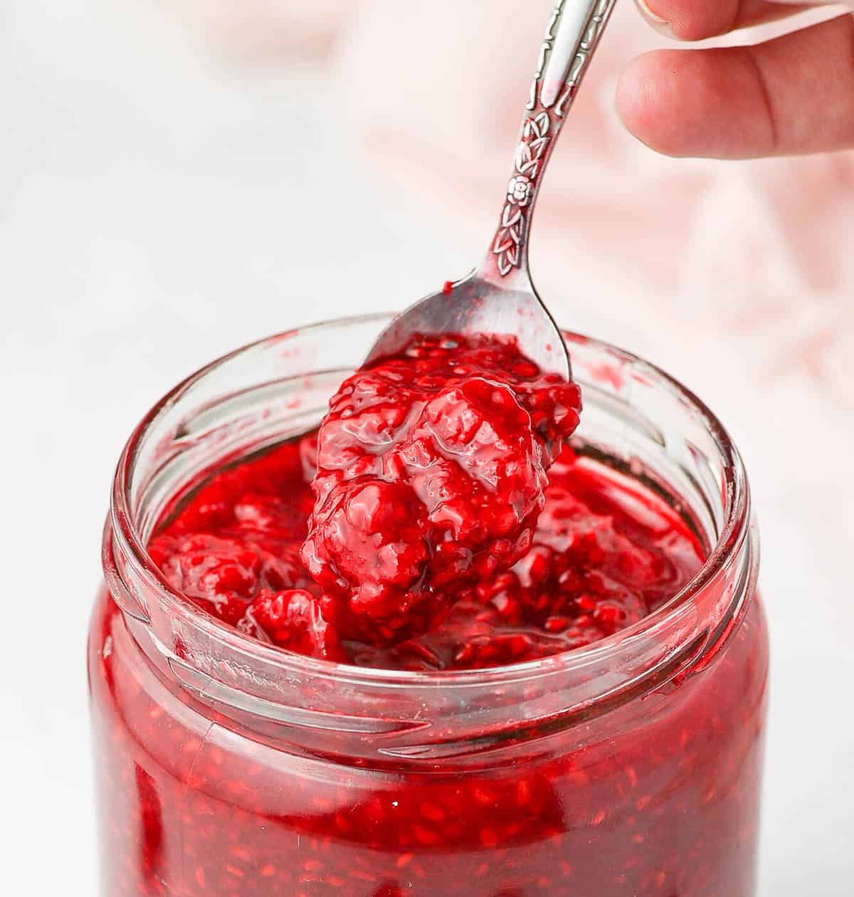 Close up on the coulis in the jar lifted on a spoon.