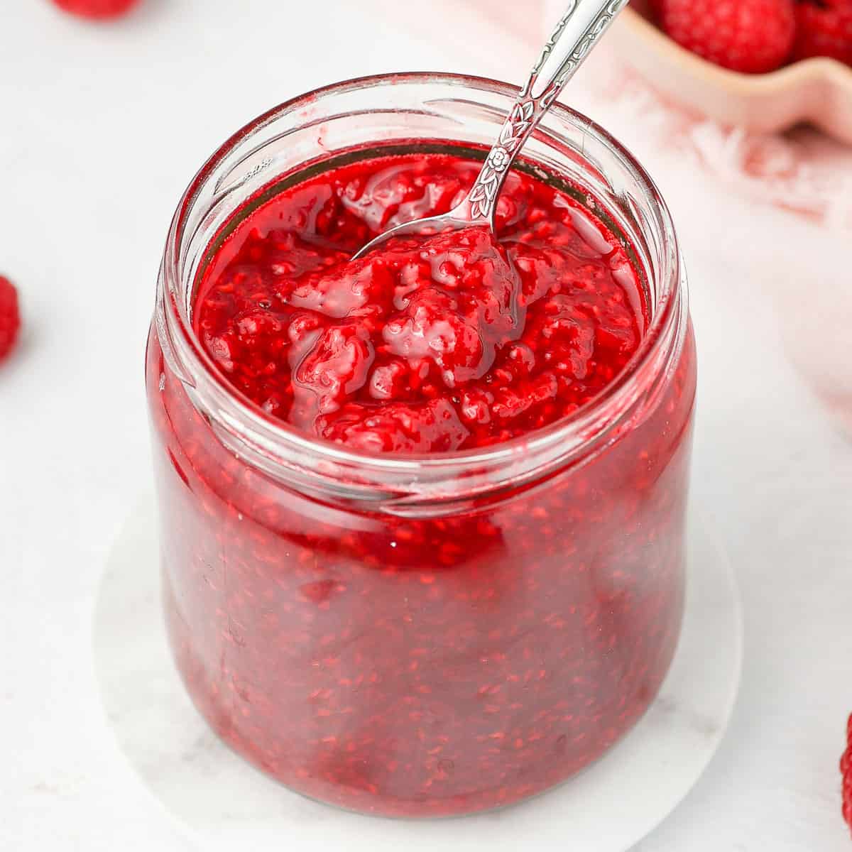Spoon sticking out of the raspberry compote jar.
