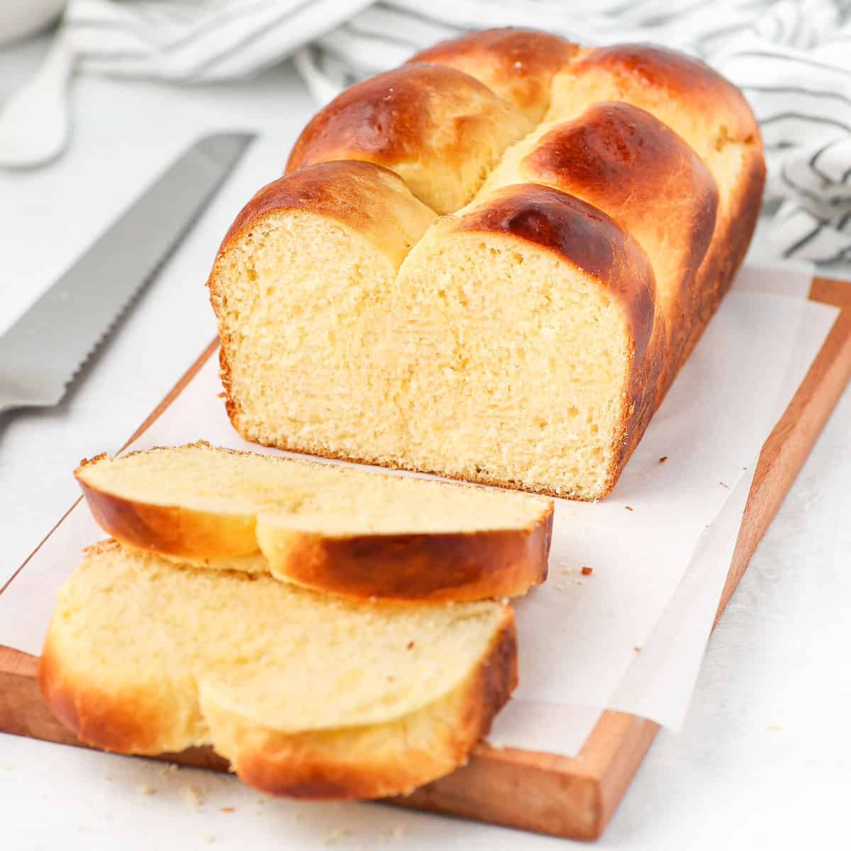 Brioche loaf sliced on a wooden board.