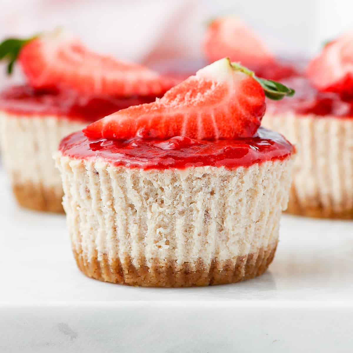 Close up on on a strawberry cheesecake placed on a grey serving tray.